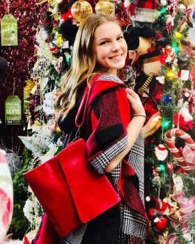 girl in front of xmas tree, showing a red purse