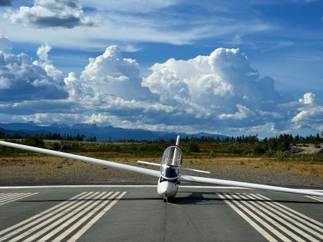 Cumulus clouds tower above a glider waiting to take off