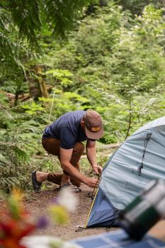 man knealing infront of tent